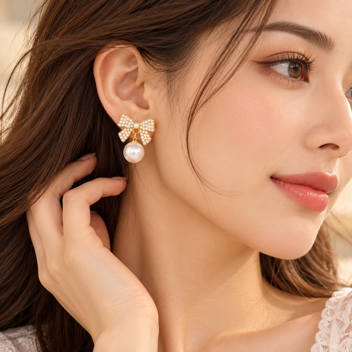 Pearl bow drop earrings arranged on champagne satin in soft luxury lighting.