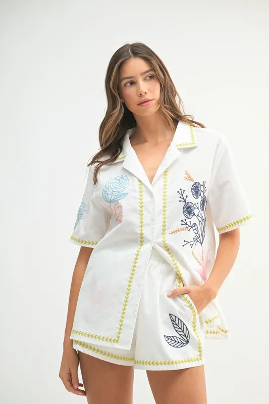 Front view of a model wearing the MABLE embroidered button-down shirt and shorts set