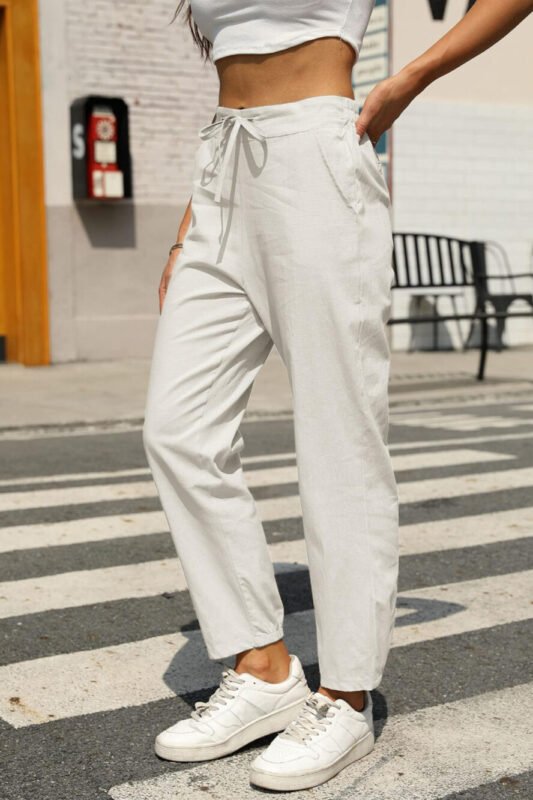 A full-length front view of a woman wearing the Gufumart white linen pants, showcasing their relaxed fit.