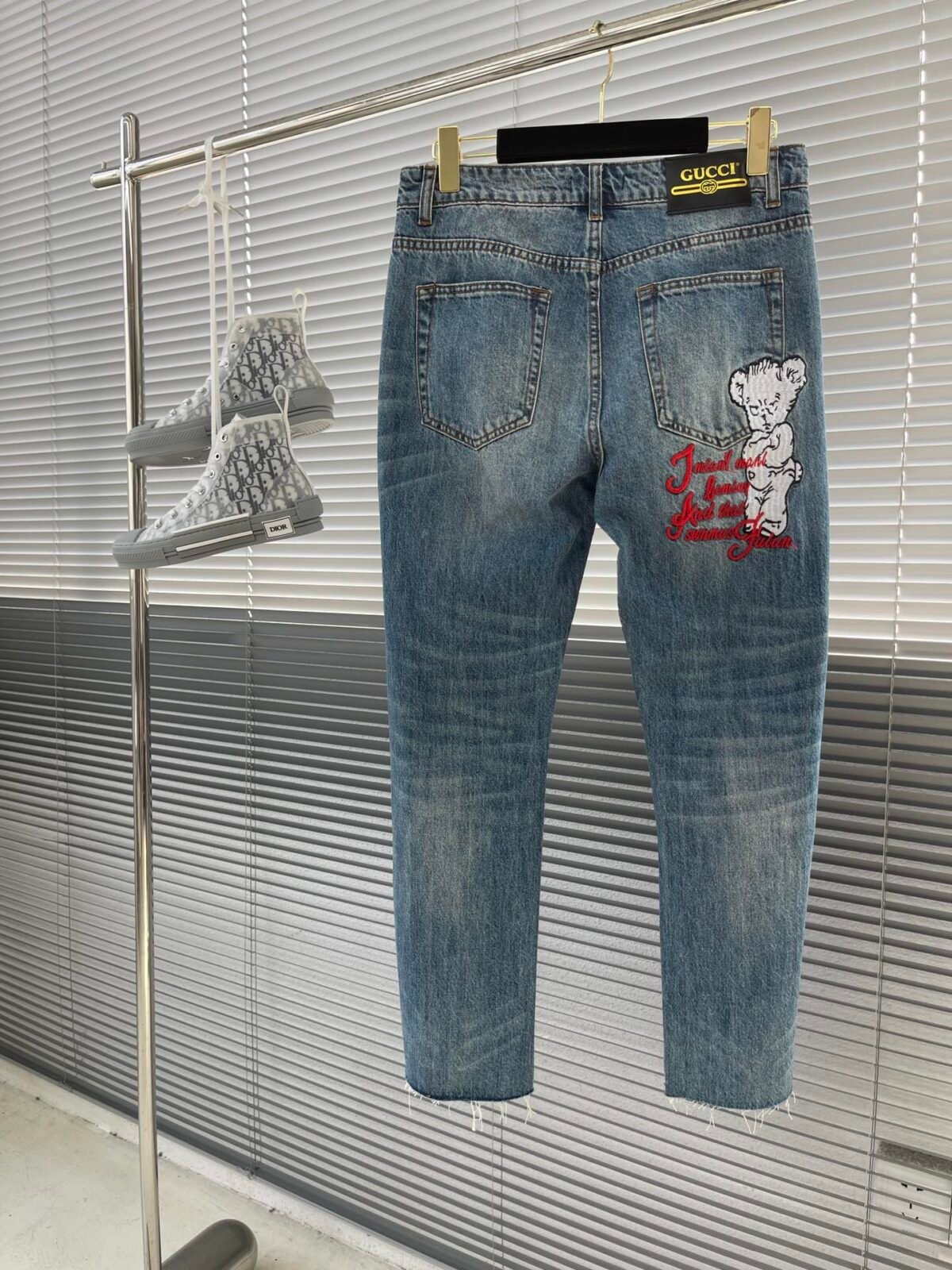 A detailed back view of the Gucci Distressed Jeans, showing the iconic engraved leather patch on the back pocket.